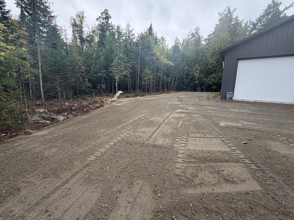The finished parking lot running down toward the woods
