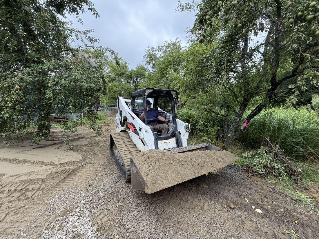 Skid steer moving material through the orchard